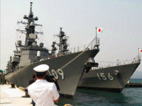 This picture taken on April 12, 2016 shows a Vietnamese Navy officer (foreground) filming two Japanese Navy's guided-missile destroyers anchored at Cam Ranh Bay in central Vietnam. The two Japanese Self-Defence Force guided-missile destroyers Ariake and Setogiri with 500 sailors aboard are paying a four-day port call at Cam Ranh Bay, which hosts Vietnam's strategic naval base. / AFP / VIETNAM NEWS AGENCY / VIETNAM NEWS AGENCY (Photo credit should read VIETNAM NEWS AGENCY/AFP/Getty Images)
