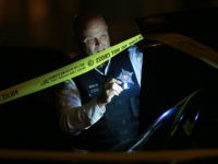 A police officer inspects a vehicle's trunk door at a crime scene in the 6800 block of South Laflin Street on Saturday, Oct. 1, 2016, in Chicago, Ill. A 20-year-old man was found shot in the alley of the street on the 6700 block and transported to Stroger Hospital. (John J. Kim/Chicago Tribune/TNS via Getty Images)