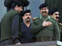 BAGHDAD, IRAQ: Iraqi President Saddam Hussein (2nd R), surrounded by body guards, salutes the crowd during a military parade in Baghdad late 20 November 2000. Thousands of Iraqis marched through the center of the Iraqi capital to demonstrate their readiness to take part in a jihad or holy war against Israel as Baghdad claims to have recruited 6.6 million volunteers to fight against Israel alongside the Palestinian uprising. AFP PHOTO/Karim SAHIB (Photo credit should read KARIM SAHIB/AFP/Getty Images)