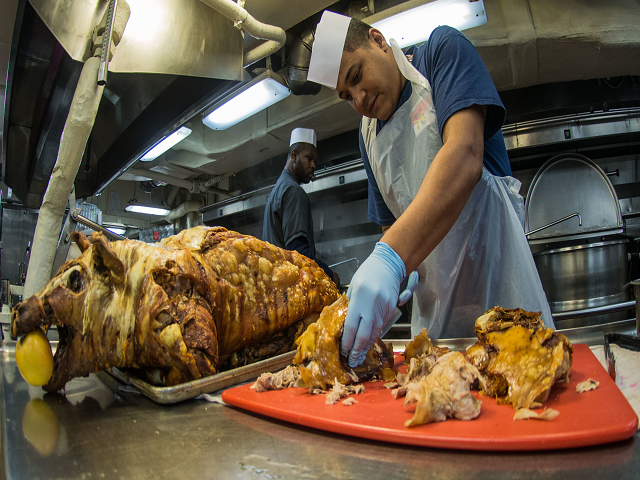 Petty Officer 1st Class Carlos Aruz cuts cooked pig in the galley during a Thanksgiving meal with shipmates and family members on the mess decks of the U.S. Navy’s only forward-deployed aircraft carrier, USS Ronald Reagan (CVN 76), after completing a scheduled three-month patrol in the Indo-Asia-Pacific region. 