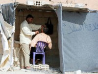 An Iraqi refugee who fled Mosul, the last major Iraqi city under the control of the Islamic State (IS) group, due to the Iraqi government forces offensive to retake the city, shaves the beard of a man at the UN-run Al-Hol refugee camp in Syria's Hasakeh province, on October 25, 2016. Despite the war that is ravaging Syria and has displaced millions of its residents, the Iraqis are desperate to reach the UN-run Al-Hol refugee camp in Syria's Hasakeh province, where many are still trapped on the border between Iraq and Syria under jihadist fire. / AFP / DELIL SOULEIMAN (Photo credit should read DELIL SOULEIMAN/AFP/Getty Images)