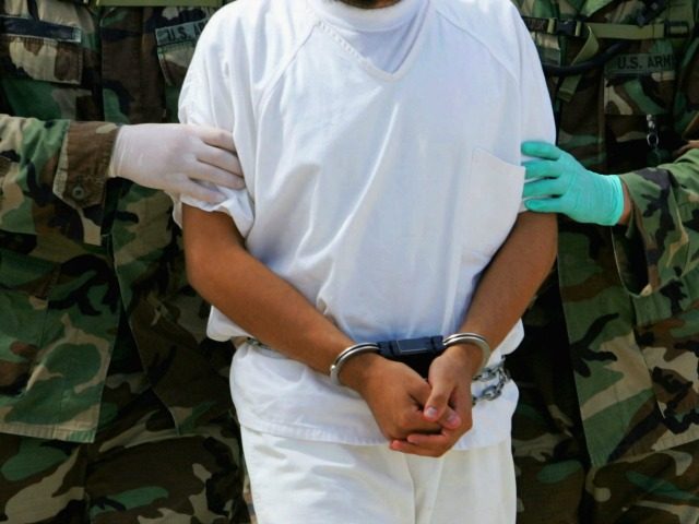 This file photo taken on August 26, 2004 shows a detainee being escorted by military police at Camp 4 of the maximum security prison Camp Delta at Guantanamo US Naval Base in Guantanamo, Cuba. Six Chinese Muslim Uighurs held at Guantanamo Bay arrived in the Pacific island nation of Palau on November 1, 2009, the latest step in US President Barack Obama's struggle to close the controversial prison. AFP PHOTO / FILES / POOL / MARK WILSON (Photo credit should read MARK WILSON/AFP/Getty Images)