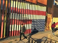 People pass graffiti along the border structure in Tijuana, Mexico, Wednesday, Jan. 25, 2017. President Donald Trump moved aggressively to tighten the nation's immigration controls Wednesday, signing executive actions to jumpstart construction of his promised U.S.-Mexico border wall and cut federal grants for immigrant-protecting 