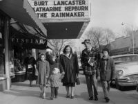 1957:  Hungarian refugee Bela Feher with his wife Lucy and their three children Vera, Cseve and Michael, walking along Main Street in Patchogue, Long Island, their new home. The film 'The Rainmaker', starring Katharine Hepburn and Burt Lancaster, is showing at the local cinema.  (Photo by Vecchio/Three Lions/Getty Images)