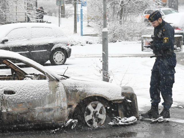 A policeman investigates a burned out car in the suburb Rinkeby, outside Stockholm, on February 21, 2017. Several cars was set in to fire after a riot in Rinkeby. The turmoil started when the police was going to arrest a man in the area. They where attacked with stones and forced use weapons. Several stores was looted and a least two persons was abused during the night. / AFP / TT News Agency / Fredrik SANDBERG / Sweden OUT (Photo credit should read FREDRIK SANDBERG/AFP/Getty Images)