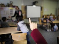 In this Tuesday, Oct. 6, 2015 photo a child rises her hand to answer a question of teacher Sandra Wiandt, background, at a so-called Willkommensklasse (Welcome Class) at the elementary school at the Baeke in Berlin, Germany. As a new school year began last month, Berlin�s schools saw non-German speaking children jump by 70 percent. There are now 478 welcome classes in the capital alone for roughly 5,000 new refugee children. (AP Photo/Markus Schreiber)