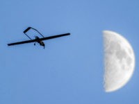 In this Oct. 20, 2015 photo, a Shadow unmanned aircraft operated by the 16th Combat Aviation Brigade over the U.S. Army Yakima Training Center in Yakima, Wash., with the moon in the background. The Army is developing the ability for Apache attack helicopter pilots to control a camera-equipped Shadow drone, allowing them to see an objective from a safer operating distance. (Peter Haley/The News Tribune via AP)