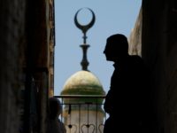 Backdropped by a mosque minaret Palestinians watch the funeral of Mohammed Al Amma, 17, in the West Bank village of Beit Ummar, near Hebron, Saturday, June 28, 2008. Al Amma was shot and killed by Israel troops during clashes in the village early Saturday morning, Palestinian medical sources said. (AP Photo/Kevin Frayer)