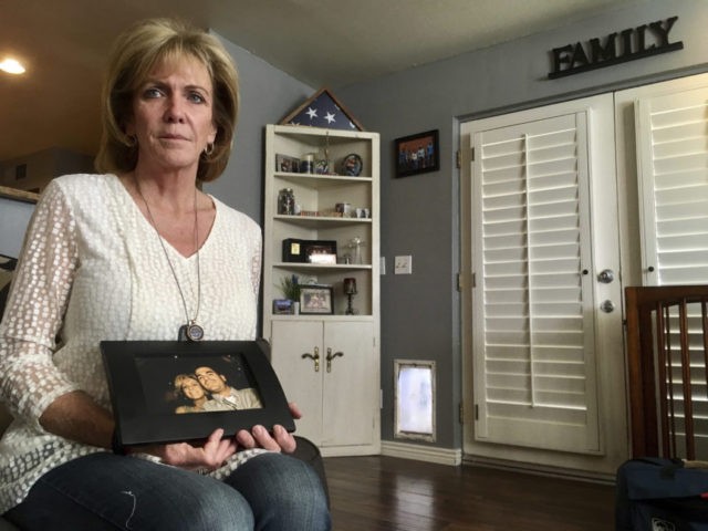 Mary Ann Mendoza poses for a photograph while holding a framed picture of herself and her son, Brandon Mendoza, on Thursday, March 2, 2017, at her home in Mesa, Ariz. Families who have lost loved ones to crimes committed by immigrants are praising President Donald Trump’s announcement this week that he will create a new office to advocate on their behalf. Mendoza's son, a Mesa police officer, was killed on May 12, 2014, in a head-on collision with a man who authorities say was intoxicated and an immigrant in the country illegally. Both Brandon Mendoza and the other diver were killed in the crash. (AP Photo/Brian Skoloff)