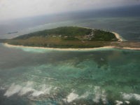 Photographed through the window of a closed aircraft, an aerial view shows Pag-asa Island, part of the disputed Spratly group of islands, in the South China Sea located off the coast of western Philippines on Wednesday July 20, 2011. A group of Filipino lawmakers flew Wednesday to the Philippine-occupied island in the disputed South China Sea to assert their country's claim to the potentially oil-rich region in defiance of China's protest that the visit threatens regional stability. (AP Photo/Rolex Dela Pena, Pool)