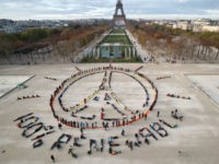Environmentalist activists form a human chain representing the peace sign and the spelling out "100% renewable", on the side line of the COP21, United Nations Climate Change Conference near the Eiffel Tower in Paris, Sunday, Dec. 6, 2015. Negotiators adopted a draft climate agreement Saturday that was cluttered with brackets and competing options, leaving ministers with the job of untangling key sticking points in what is envisioned to become a lasting, universal pact to fight global warming. (AP Photo/Michel Euler)