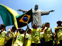 Brazilian schoolboys wave flags and cheer in front of the statue to Christ the Redeemer 30 October, 2007 in Rio de Janeiro, Brazil. Brazil, the only runner in the race, was officially unveiled as the 2014 World Cup host by FIFA president Sepp Blatter in Zurich Tuesday. The five-time world champions have staged the World Cup once before, in 1950, when they lost the final 2-1 to Uruguay in front of a near 200,000 crowd at the Maracana stadium in Rio de Janeiro. AFP PHOTO ANTONIO SCORZA (Photo credit should read ANTONIO SCORZA/AFP/Getty Images)