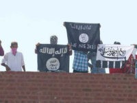 SRINAGAR, INDIA - AUGUST 28: Masked Kashmiri youth hold ISIS, Lashkar-e-Taiba flags and posters of Pakistan founder Mohammad Ali Jinnah and former ISI Chief Hamid and local militant commander of Hizbul Mujahideen Burhan during a protest outside Jamia Masjid in downtown Srinagar, on August 28, 2015 in Srinagar, India. The police had to fire tear gas shells to disperse the stone-pelting mob and restore law and order. (Photo by Abid Bhat/Hindustan Times via Getty Images)
