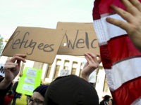 A protester against the United States' acceptance of Syrian refugees uses a U.S. flag to block a counter-protester's sign that read ''Refugees Welcome'' during a demonstration at the Washington State capitol in Olympia, Washington, November 20, 2015. REUTERS/David Ryder