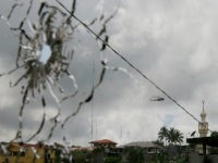 A military helicopter hovering by a mosque is seen through a shattered glass brought about by the fighting between government troops and Muslim militants who continue to hold their ground in some areas of Marawi city for almost a week Monday, May 29, 2017 in southern Philippines. Philippine forces control most of a southern city where militants linked to the Islamic State group launched a bloody siege nearly a week ago, authorities said Monday, as the army launched airstrikes and went house-to-house to crush areas of resistance. (AP Photo/Bullit Marquez)