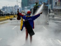 Opposition activist Wuilly Arteaga stands with a violin in front of an armoured vehicle of the riot police during a protest against President Nicolas Maduro in Caracas, on May 24, 2017. Venezuela's President Nicolas Maduro formally launched moves to rewrite the constitution on Tuesday, defying opponents who accuse him of clinging to power in a political crisis that has prompted deadly unrest. / AFP PHOTO / FEDERICO PARRA (Photo credit should read FEDERICO PARRA/AFP/Getty Images)