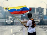 A Venezuelan opposition demonstrator waves a national flag in front of the riot police during a protest against President Nicolas Maduro, in Caracas, on May 8, 2017