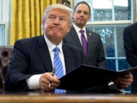 TOPSHOT - US President Donald Trump signs an executive order as Chief of Staff Reince Priebus looks on in the Oval Office of the White House in Washington, DC, January 23, 2017. Trump on Monday signed three orders on withdrawing the US from the Trans-Pacific Partnership trade deal, freezing the hiring of federal workers and hitting foreign NGOs that help with abortion. / AFP / SAUL LOEB (Photo credit should read SAUL LOEB/AFP/Getty Images)