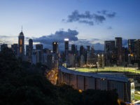 The Hong Kong Jockey Club's Happy Valley racecourse sits surrounded by buildings at dusk in Hong Kong, China, on Wednesday, June 7, 2017. One of the city's most-venerable institutions, the Hong Kong Jockey Club, which has been called an 'ATM for the government' for its huge contributions to the city's tax coffers and charity efforts, is facing trouble. Disinterest among many young people and an upcoming bridge link to the glittering casinos of Macau threaten the future of the money-spinning gambling monopoly. Photographer: Justin Chin/Bloomberg via Getty Images