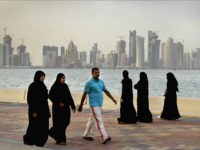 FILE- In this Saturday, April 7, 2012 file photo, the new high-rise buildings of downtown Doha, photographed in the background as Qatari women and a man walk by the sea in Doha, Qatar. Qatar, now facing a diplomatic crisis with other Arab nations, is a small country with a big history of turmoil and coups as it became one of the world's top suppliers of natural gas and now plans to host the 2022 FIFA World Cup. (AP Photo/Kamran Jebreili, File)