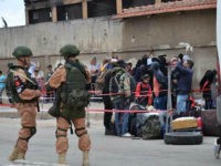 Russian troops (L) stand guard as Syrian opposition fighters and their families board a bus at a checkpoint manned by regime forces ahead of their evacuation from Waer neighbourhood, the last opposition-held district in the central city of Homs, on May 20, 2017. In five months, the Syrian rebels, crushed by the regime's troops backed by Russia and Iran, lost their stronghold Aleppo, Syria's second city, their last quarters in Damascus and now the Waer district, their last bastion in Homs. / AFP PHOTO / STRINGER (Photo credit should read STRINGER/AFP/Getty Images)