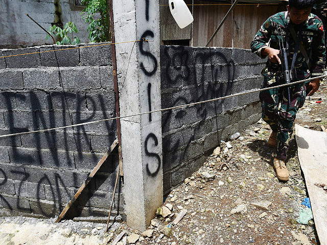 An army trooper walks past graffiti on a concrete fence near the frontline in Marawi on the southern island of Mindanao on June 22, 2017, as fighting between government troops and Islamist militants entered its fourth week. The fighting began on May 23 when hundreds of militants rampaged through Marawi, the most important Muslim city in the mainly Catholic Philippines, waving the black flags of the Islamic State (IS) group. / AFP PHOTO / TED ALJIBE (Photo credit should read TED ALJIBE/AFP/Getty Images)