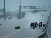 Evacuation residents from the Meyerland area walk onto an I-610 overpass for further help during the aftermath of Hurricane Harvey August 27, 2017 in Houston, Texas. Hurricane Harvey left a trail of devastation Saturday after the most powerful storm to hit the US mainland in over a decade slammed into Texas, destroying homes, severing power supplies and forcing tens of thousands of residents to flee. / AFP PHOTO / Brendan Smialowski (Photo credit should read BRENDAN SMIALOWSKI/AFP/Getty Images)