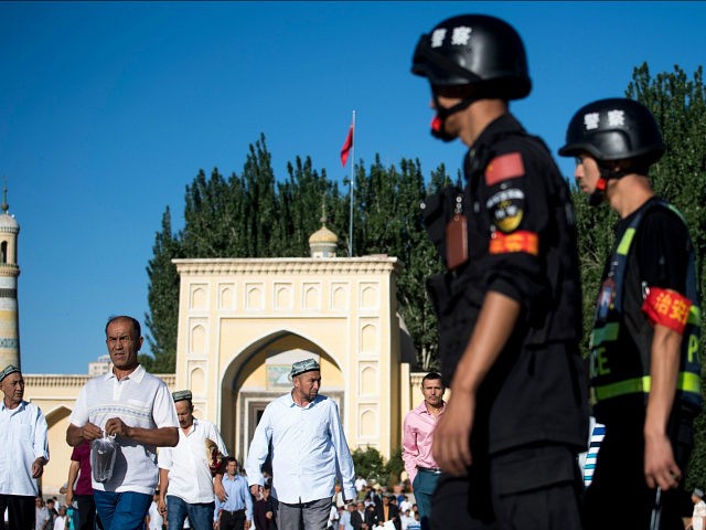 This picture taken on June 26, 2017 shows police patrolling as Muslims leave the Id Kah Mosque after the morning prayer on Eid al-Fitr in the old town of Kashgar in China's Xinjiang Uighur Autonomous Region. The increasingly strict curbs imposed on the mostly Muslim Uighur population have stifled life …