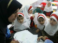 Iranian girls gather around their teacher in the clasroom at Sizdah Abban school in north of Tehran 01 October 2006. Iranian students went back to school a week ago. US President George W. Bush signed into law yesterday a set of sanctions targeting foreign countries that continue nuclear cooperation with Iran and sell it advanced weaponry. The measure, passed by the Senate Saturday after clearing the House of Representatives a day earlier, came as Iran and the European Union are engaged in delicate negotiations designed to persuade Iran to halt its enrichment work and avoid a major international showdown. AFP PHOTO/ATTA KENARE ATTA KENARE / AFP
