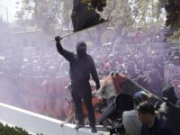 An anti-fascist demonstrator jumps over a barricade during a free speech rally Sunday, Aug. 27, 2017, in Berkeley, Calif. Several thousand people converged in Berkeley Sunday for a "Rally Against Hate" in response to a planned right-wing protest that raised concerns of violence and triggered a massive police presence. Several people were arrested for violating rules against covering their faces or carrying items banned by authorities. (AP Photo/Marcio Jose Sanchez)