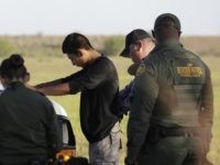 In this Aug. 11, 2017, photo, immigrants suspected of crossing into the United States illegally along the Rio Grande near Granjeno, Texas, are held by U.S. Customs and Border Patrol agents. After hitting a 17-year low shortly after President Donald Trump took office, the numbers of people coming over the border have risen four months in a row. (AP Photo/Eric Gay)
