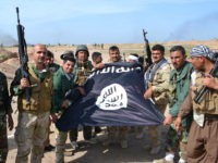 Iraqi Kurdish Peshmerga fighters pose for a photo holding an Islamic State (IS) group flag in the village of Sultan Mari west of the city of Kirkuk on March 9, 2015 after they reportedly re-took the area from IS jihadists. IS spearheaded a sweeping offensive in June 2014 that overran large parts of the country north and west of Baghdad, including in Kirkuk province. AFP PHOTO / MARWAN IBRAHIM (Photo credit should read MARWAN IBRAHIM/AFP/Getty Images)