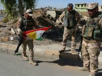 Iraqi soldiers remove a Kurdish flag from a checkpoint in Bashiqa, Iraq, Wednesday, Oct. 18, 2017. Iraqi forces took control of the mixed Yazidi-Christian town of Bashiqa on the northeastern outskirts of Mosul on Tuesday. Kurdish forces pulled out of disputed areas across northern and eastern Iraq a day after handing Kirkuk to federal forces amid a tense standoff following last month's vote for independence. (AP Photo/Khalid Mohammed)