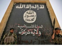 Fighters from the Hashed al-Shaabi (Popular Mobilisation units), backing the Iraqi forces, stand in front of a mural depicting the emblem of the Islamic State (IS) group as troops advance through Hawija on October 5, 2017, after retaking the city from Islamic State (IS) group fighters. Iraqi forces retook one of the Islamic State group's last two enclaves in the country on October 5, overrunning the longtime insurgent bastion of Hawija after a two-week offensive. / AFP PHOTO / AHMAD AL-RUBAYE (Photo credit should read AHMAD AL-RUBAYE/AFP/Getty Images)