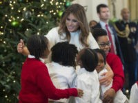 US First Lady Melania Trump hugs children in the East Room as she tours Christmas decorations at the White House in Washington, DC, November 27, 2017. / AFP PHOTO / SAUL LOEB