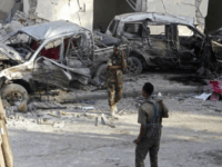 Somali soldiers stand near the wreckage of vehicles in Mogadishu, Somalia, Sunday, Oct 29, 2017, after a car bomb detonated Saturday night. A Somali police officer said security forces ended a night-long siege at a Mogadishu hotel by attackers who stormed the building after a suicide car bomber detonated an explosives-laden vehicle at the entrance gate. (AP Photo/Farah Abdi Warsameh)
