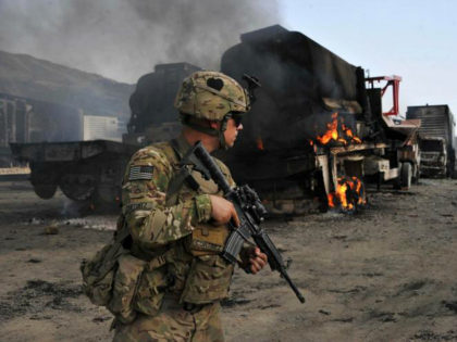 A US soldier investigates the scene of a suicide attack at the Afghan-Pakistan border crossing in Torkham, Nangarhar province on June 19, 2014. Three Taliban suicide attackers set ablaze 37 NATO military vehicles in Afghanistan on June 19, local officials said, though the coalition confirmed only that several vehicles were damaged. AFP PHOTO/Noorullah Shirzada (Photo credit should read Noorullah Shirzada/AFP/Getty Images)
