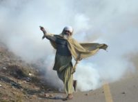 A Pakistani protester of the Tehreek-i-Labaik Yah Rasool Allah Pakistan religious group throws a tear gas shell back towards police during a clash in Islamabad on November 25