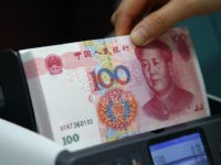 An employee puts Chinese one-hundred yuan banknotes in a money counting machine for a photograph at the Korea Exchange Bank headquarters in Seoul, South Korea, on Thursday, Feb. 27, 2014. Chinas central bank is forecast to double the yuans trading band in the coming quarter as policy makers loosen exchange-rate controls to promote greater usage of the currency in global trade and finance. Photographer: SeongJoon Cho/Bloomberg via Getty Images