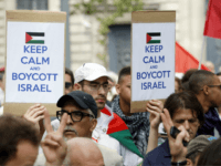 A Pro-Palestinian demonstrator carries placards reading 'Keep calm and boycott Israel' on the Republique square in Paris, ahead of a banned demonstration against Israel's military operation in Gaza and in support of the Palestinian people, on July 26, 2014. French authorities banned on July 26, 2014 a new pro-Palestinian demonstration over concerns it could turn violent as previous rallies have, but demonstrators may ignore the ban as they did last weekend. US Secretary of State John Kerry and other top diplomats from Europe and the Middle East began talks in Paris on July 26 to press efforts for a long-term ceasefire between Israel and Hamas. AFP PHOTO / KENZO TRIBOUILLARD (Photo credit should read KENZO TRIBOUILLARD/AFP/Getty Images)