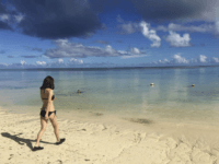 A tourist enters the waters of Tumon Bay on the island of Guam, Tuesday, Aug. 15, 2017. The nuclear conflict with North Korea that has made Guam the target of a threatened attack has led to new calls to change the government of the Pacific island whose inhabitants are American citizens but have no say in electing the president or the use of military force. (AP Photo/Tassanee Vejpongsa)
