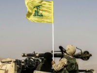 A picture taken on August 2, 2017 during a tour guided by the Lebanese Shiite Hezbollah movement shows one of the group's fighters flying the group's flag as he sits in a four-wheel drive vehicle carrying a recoilless rifle, in a mountainous area around the Syrian town of Flita near the border with Lebanon. / AFP PHOTO / LOUAI BESHARA (Photo credit should read LOUAI BESHARA/AFP/Getty Images)