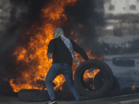 A Palestinian protester burns tires during clashes with Israeli troops following protests against U.S. President Donald Trump's decision to recognize Jerusalem as the capital of Israel, in the West Bank city of Ramallah, Thursday, Dec. 7, 2017. (AP Photo/Nasser Nasser)