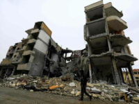 A picture taken on October 28, 2017, shows a fighter of the Syrian Democratic Forces (SDF) walking through an empty rubble-filled street surrounded by damaged buildings in the Syrian city of Raqa. The US-backed SDF took full control of Raqa on October 17, wrapping up an operation that lasted more than four months to capture a city that had been the inner sanctum of IS's now moribund 'caliphate'. Hundreds of thousands of people fled the city since 2014 and by the time the SDF retook it, Raqa had become a ghost town of collapsed buildings. / AFP PHOTO / Delil souleiman (Photo credit should read DELIL SOULEIMAN/AFP/Getty Images)