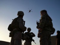 In this photograph taken on August 27, 2017 US Marines and Afghan Commandos stand together as an Afghan Air Force helicopter flies past during a combat training exercise at Shorab Military Camp in Lashkar Gah in Helmand province. Marines in Afghanistan's Helmand say Donald Trump's decision to keep boots on the ground indefinitely gives them 'all the time in the world' to retake the province, once the symbol of US intervention but now a Taliban stronghold. They may need it. At the hot, dusty Camp Shorab, where many of the recently deployed Marines train their Afghan counterparts in flat, desert terrain, the Afghans admit their army still cannot fight alone. / AFP PHOTO / WAKIL KOHSAR (Photo credit should read WAKIL KOHSAR/AFP/Getty Images)