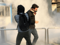 Iranian students run for cover from tear gas at the University of Tehran during a demonstration driven by anger over economic problems, in the capital Tehran on December 30, 2017. Students protested in a third day of demonstrations, videos on social media showed, but were outnumbered by counter-demonstrators. / AFP PHOTO / STR (Photo credit should read STR/AFP/Getty Images)