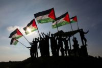 Palestinian protesters wave their national flag near the Israel-Gaza border east of the southern Gaza Strip city of Khan Yunis as they demonstrate efforts to close UNRWA and possible US cuts Palestinian aid
