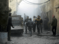 This photo released on Saturday, Feb 24, 2018 by the Syrian Civil Defense group known as the White Helmets, shows members of the Syrian Civil Defense group and civilians gathering to help survivors from a street attacked by airstrikes and shelling by Syrian government forces, in Ghouta, a suburb of Damascus, Syria. A new wave of airstrikes and shelling on eastern suburbs of the Syrian capital Damascus left at least 22 people dead and more than a dozen wounded Saturday, raising the death toll of a week of bombing in the area to nearly 500, including scores of women and children. (Syrian Civil Defense White Helmets via AP)