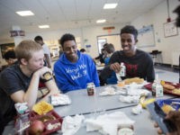 Abdiaziz Shaleh, right, a Lewiston high school senior and co-captain of the soccer team, and Essa Gedi, center, both whose families emigrated from Somalia, sit with classmate Isiah Leach, left, during lunch in the school's cafeteria in Lewiston, Maine, Wednesday, March 15, 2017. Two years ago, immigrant children led the high school soccer team to win the state championship, a moment heralded as a triumph for the city's embrace of its immigrant community. (AP Photo/David Goldman)
