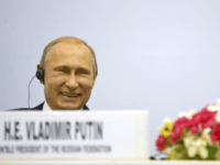 Russian President Vladimir Putin share a laugh as they attend a session of the World Diamond Conference in New Delhi, India, Thursday, Dec. 11, 2014. Putin was holding talks with Indian leaders Thursday to strengthen trade and energy cooperation with Asia's third-largest economy as Western sanctions threaten to push his country's economy to the brink of a recession. (AP Photo/ Saurabh Das)